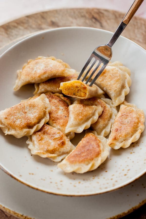 Vegan pierogi with lentil and sun-dried tomato filing on a light brown plate.