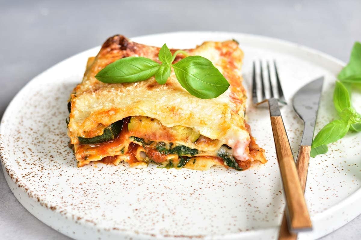 A piece of zucchini spinch lasagna on a white plate.