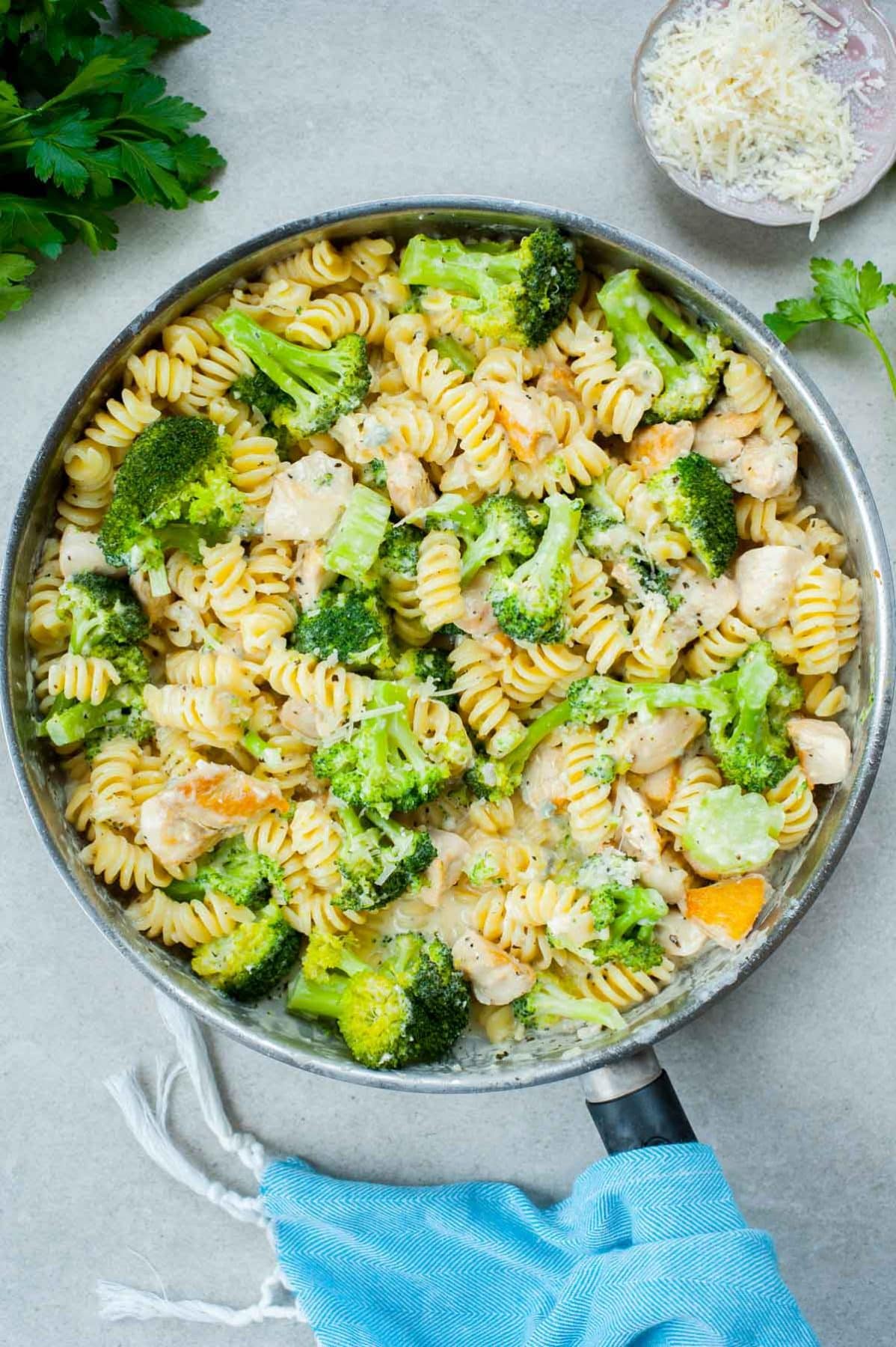 Pasta with cheese sauce, chicken and broccoli in a frying pan.