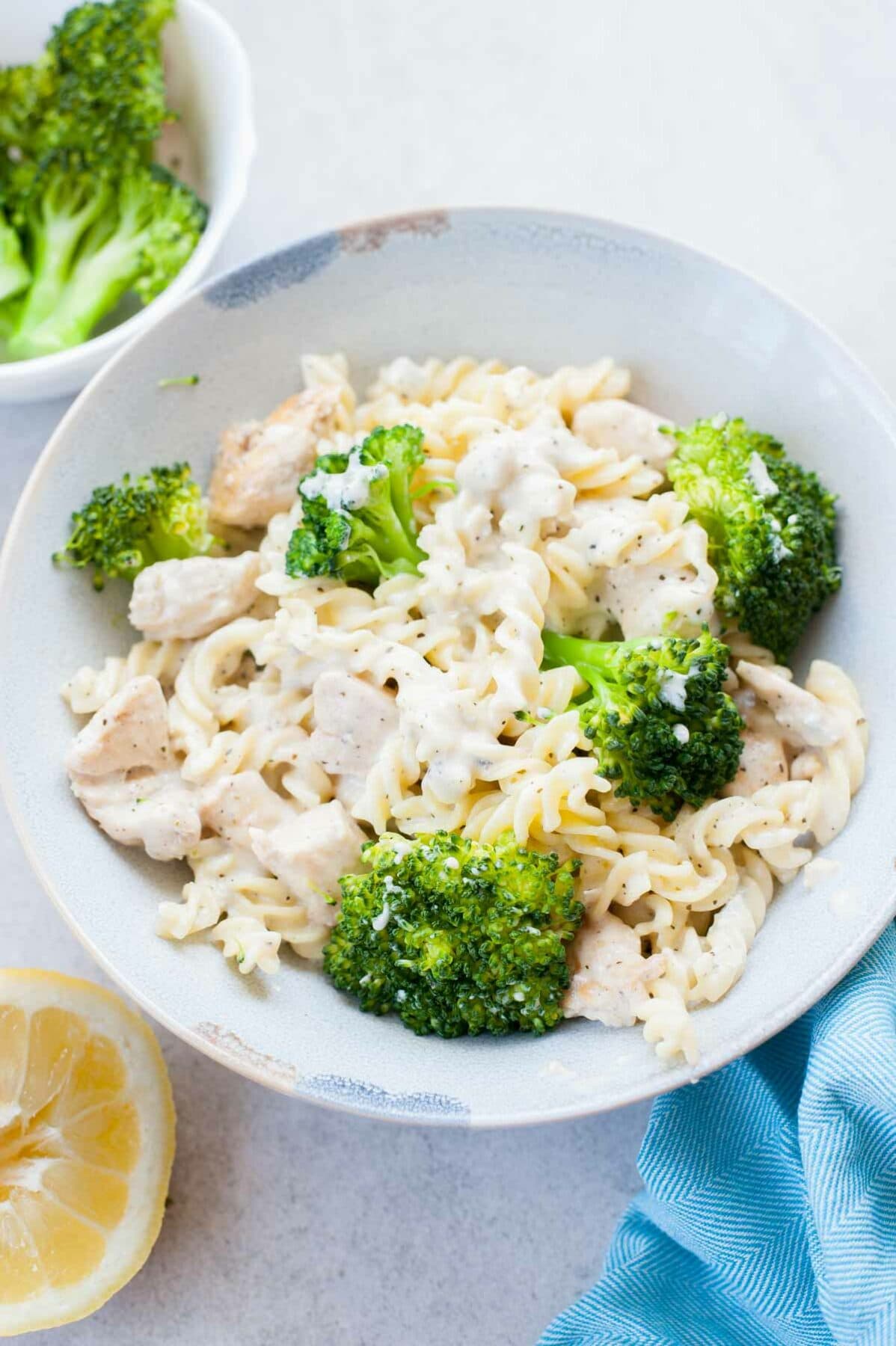 Chicken with cheese sauce and broccoli in a blue plate.