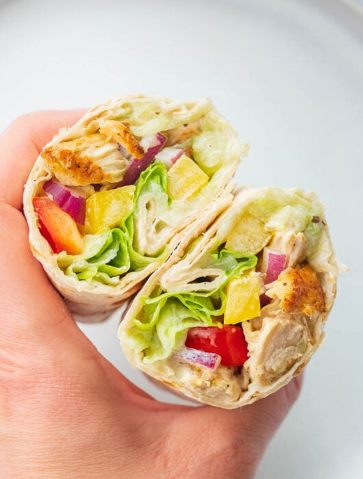 Greek chicken wraps held in a hand.