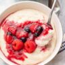 Semolina pudding with berry compote in a white bowl.