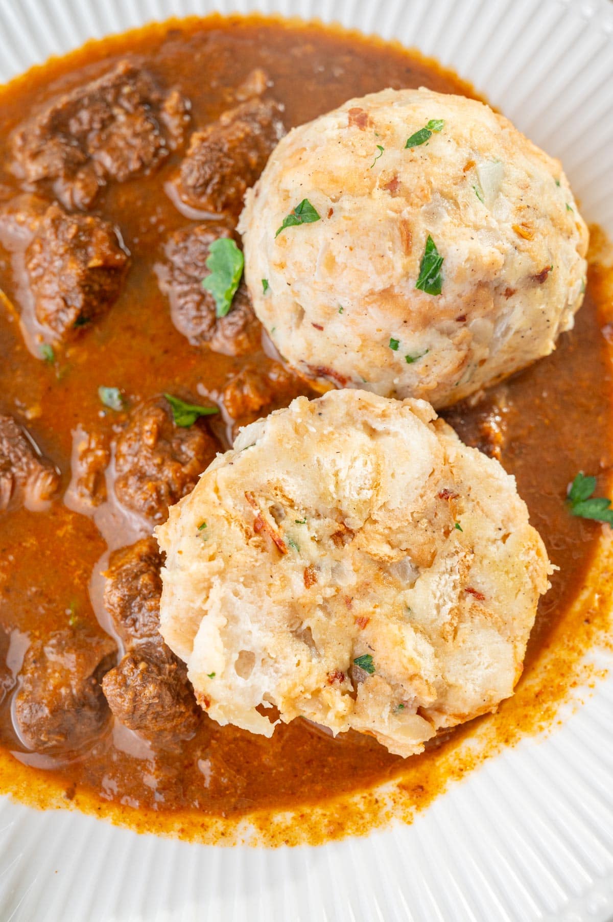 A close up photo of Semmelknödel served with beef goulash.