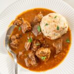 Viennese goulash served with Semmelknödel in a white plate.