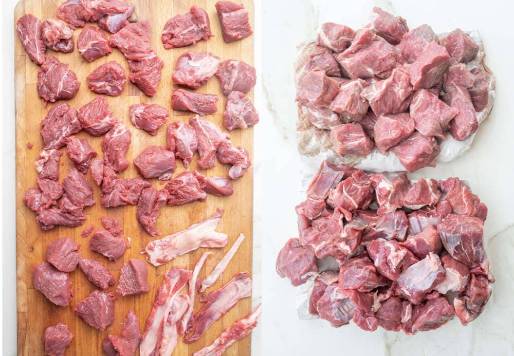 Cubes of beef on a chopping board and white marble counter. 