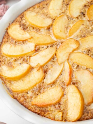 A close up photo of baked peach oatmeal in a white baking dish.