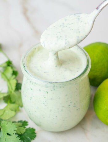 Cilantro lime crema in a jar. Cilantro and limes in the background.