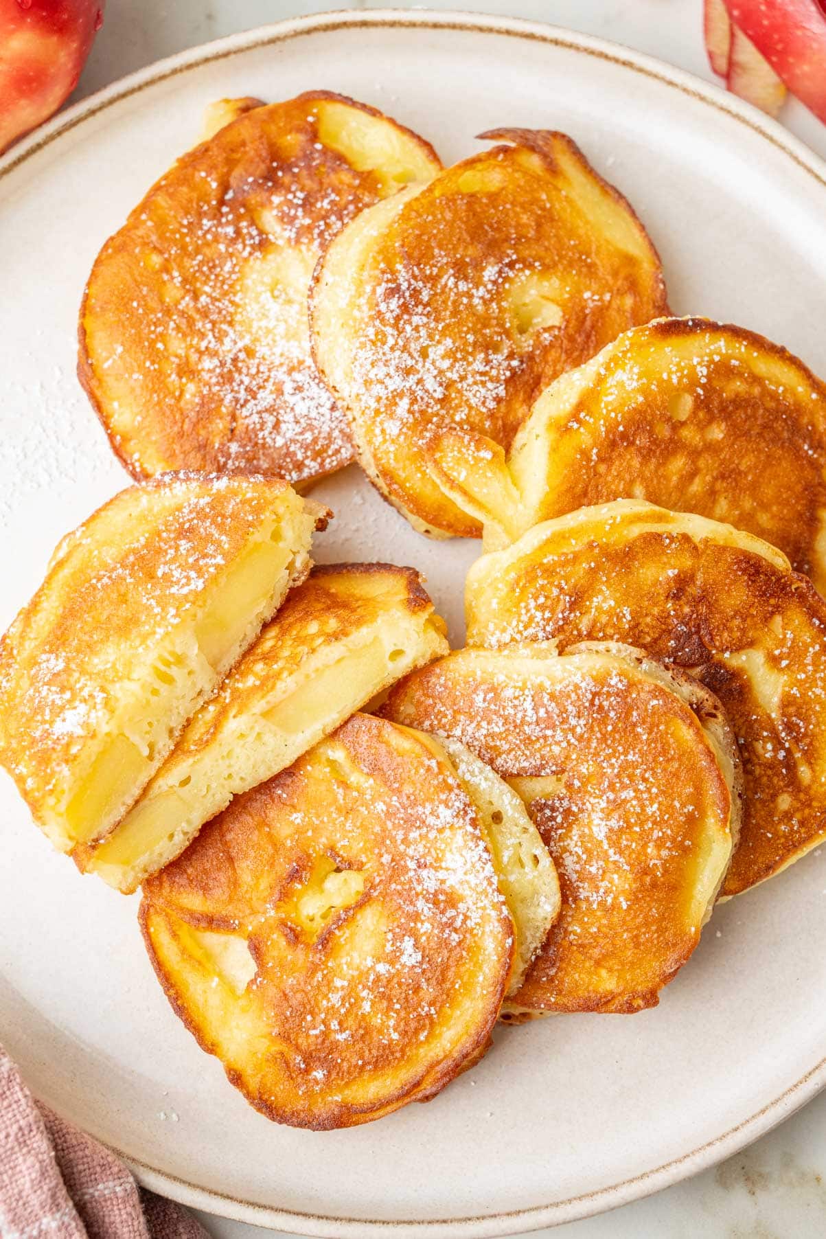 An overhead photo of apple ring pancakes on a beige plate.