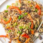 Ground beef noodles with vegetables on a white plate.