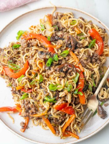 Ground beef noodles with vegetables on a white plate.