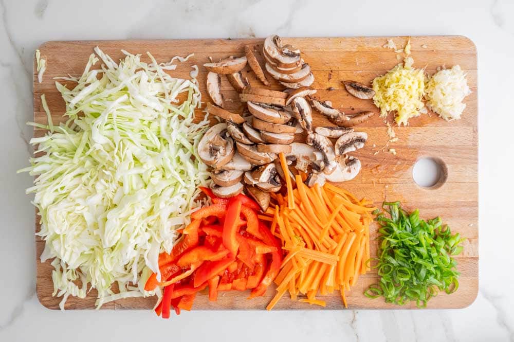 Chopped vegetables and mushrooms on a wooden board.