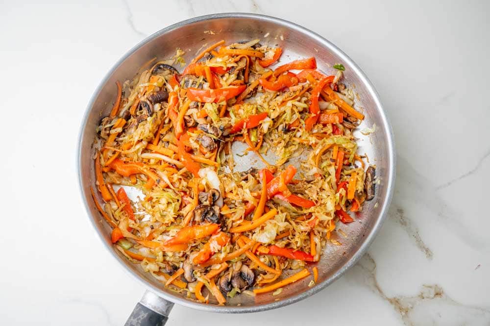 Stri-fried vegetables and mushrooms in a pan.