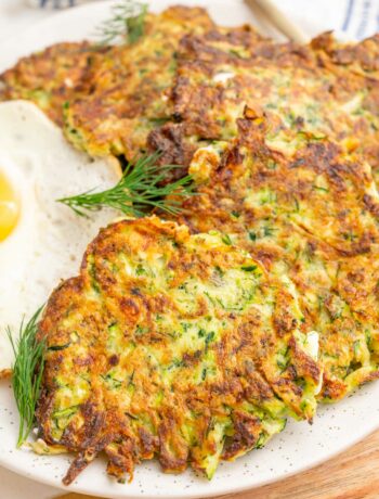 A close up photo of zucchini fritters on a white plate.