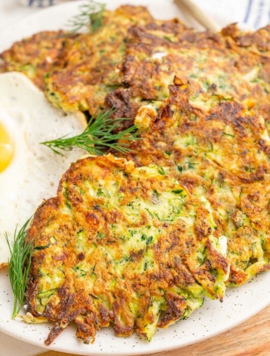 A close up photo of zucchini fritters on a white plate.