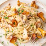 Creamy chanterelle pasta on a beige plate.