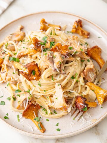 Creamy chanterelle pasta on a beige plate.