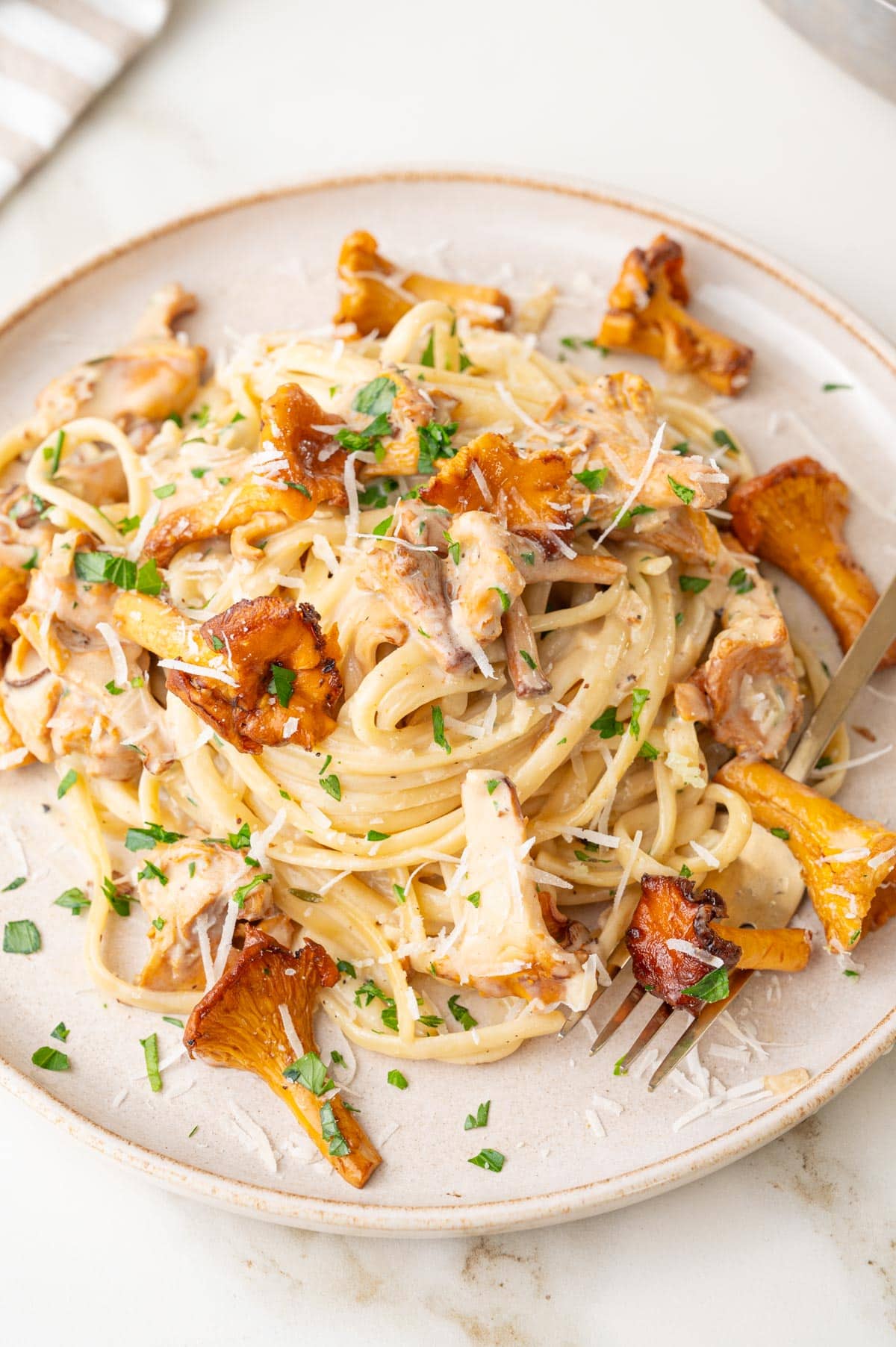 Creamy chanterelle pasta on a beige plate.