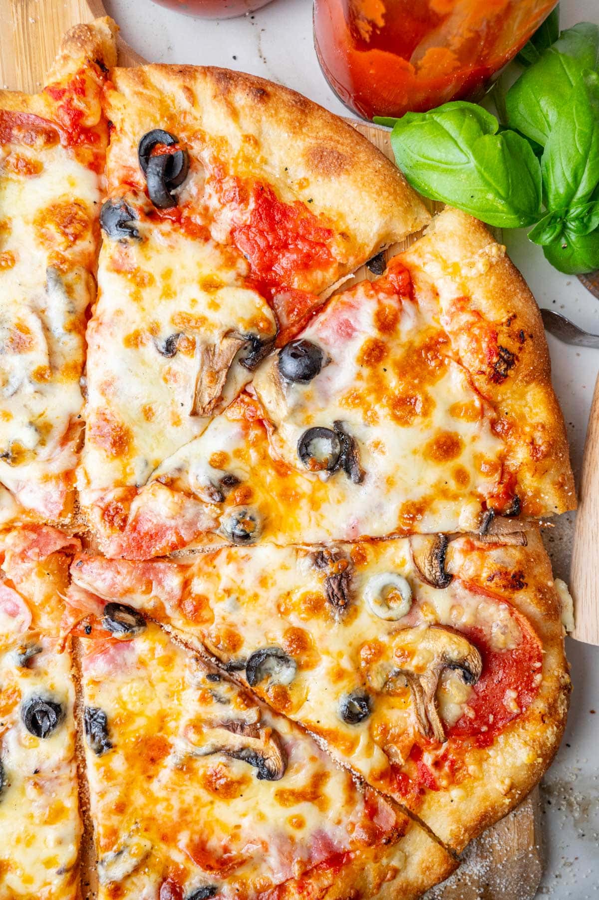 A close up photo of pizza with salami, cheese, mushrooms, and olives.