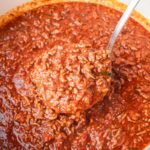 Spaghetti meat sauce in a white pot with a ladle inside.