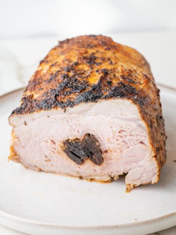 Polish pork loin roast stuffed with prunes cut in half on a plate.