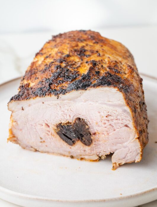 Polish pork loin roast stuffed with prunes cut in half on a plate.